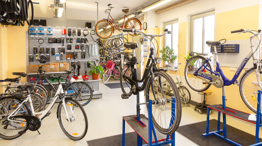 Blick in die Fahrradwerkstatt mit verschiedenen Rädern, die zur Reparatur aufgestellt sind