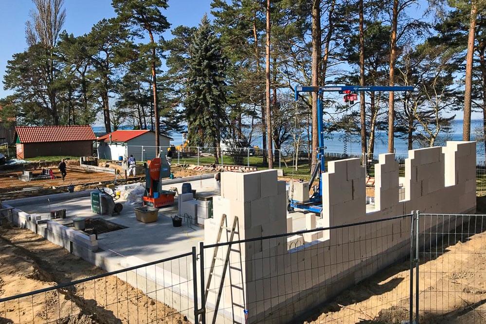 Eine Betonplatte liegt auf der sandigen Baufläche und erste Mauerteile ragen aus hier heraus
