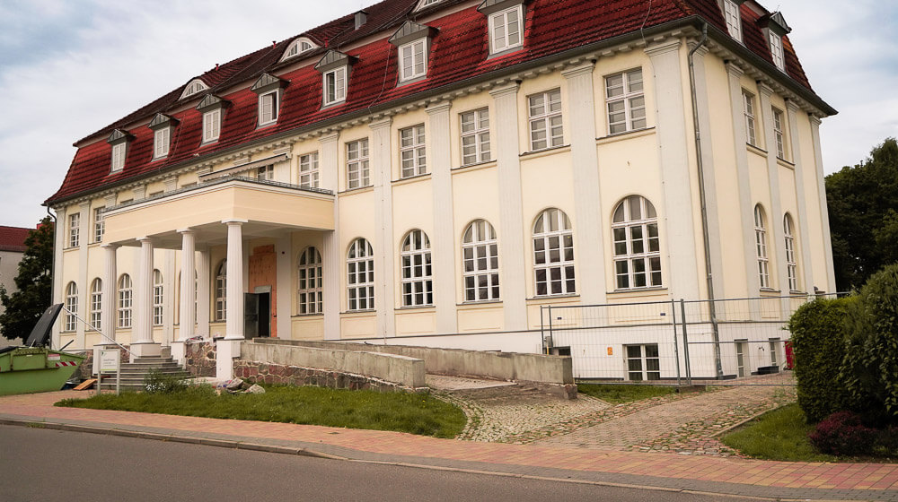 Eine dreistöckige Villa mit einer überdachten Einfahrt, auf der Fahrzeuge direkt an das Gebäude fahren können