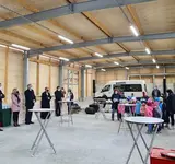 Eine Gruppe von Menschen steht mir einigen Tischen in der neuen Halle