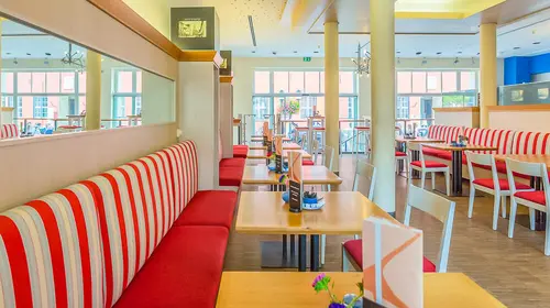 Der Gastraum des Lichtblick mit Sitzbänken, Tischen, Stühlen und Speisekarten auf den Tischen