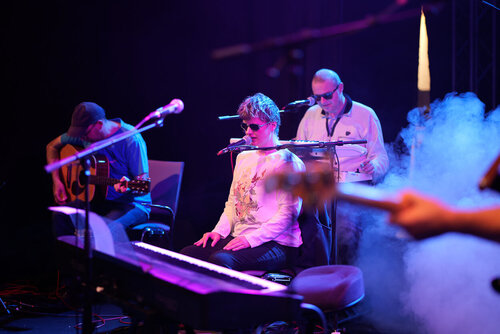 Nicole Vollbrecht spielt an einem Keyboard, umringt von den anderen Mitgliedern der Band