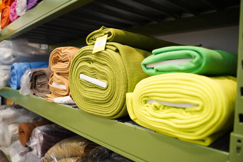 In einem Regal liegen übereinander Stoffrollen in unterschiedlichen Farben