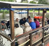 Eine Gruppe älterer Herrschaften fährt in einem großen Floß auf dem Wasser