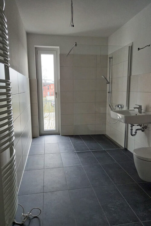 Tageslichtbadezimmer mit Waschbecken, ebenerdiger Dusche und Handtuchheizung