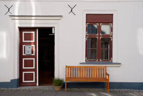 Ein Hauseingang mit einer geöffneten Haustür und einer Sitzbank davor