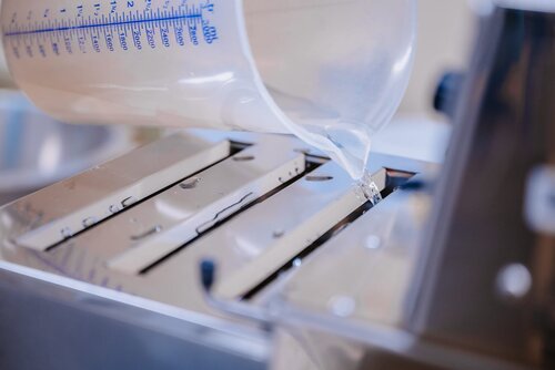 Wasser wird aus einem Messbecher in ein Portionierer geschüttet