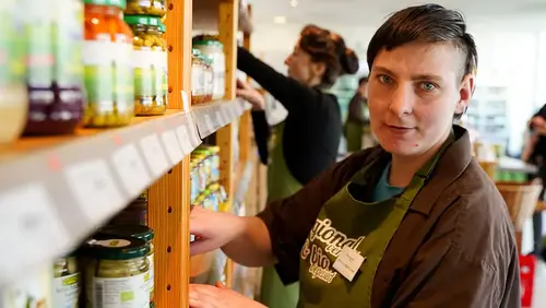 Eine Mitarbeiterin in Arbeitskleidung steht an einem Regal im Pommerngrün