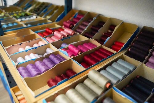 Viele Rollen Garn in unterschiedlichen Farben lagern in mehreren Kästen nebeneinander