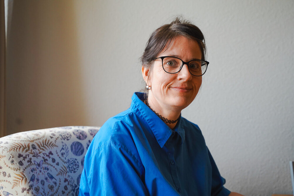 Eine Frau sitzt auf einem Sessel und lächelt in die Kamera