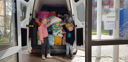 Zwei Kinder stehen vor dem vor beladenen Transporter