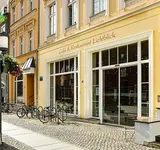Außenansicht des Café und Restaurant Lichtblick vom Greifswalder Rathaus aus mit Aufsteller Mittagstisch und Blumenschmuck