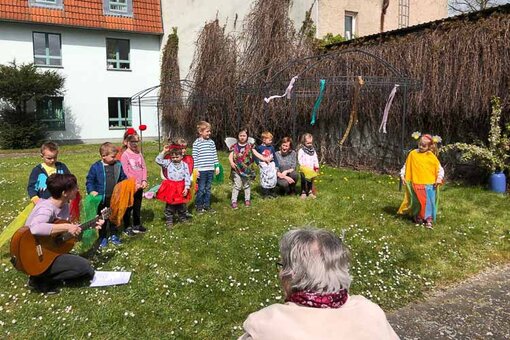 Eine Gruppe kleiner Kinder singt auf einer Wiese