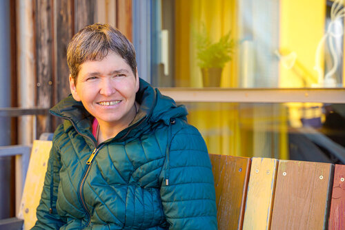 Eine Frau in einer Jacke sitzt auf einer Bank