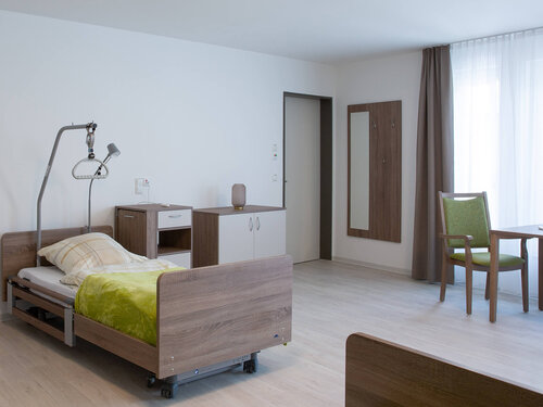 Bewohnerzimmer mit Bett, Stuhl und Tisch