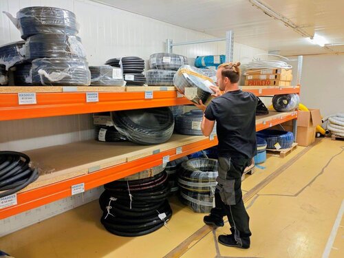 Verpackte Industrieschläuche lagern in einem großen Regal. 