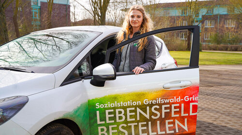 Eine Pflegefachkraft unseres Pflegedienst Greifswald - Griebenow sitzt in ihrem Fahrzeug und lächelt 