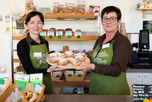 Zwei Verkäuferinnen präsentieren frische gezuckerte Backwaren 