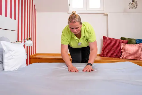 Eine Mitarbeiterin streicht in Bettlaken gerade