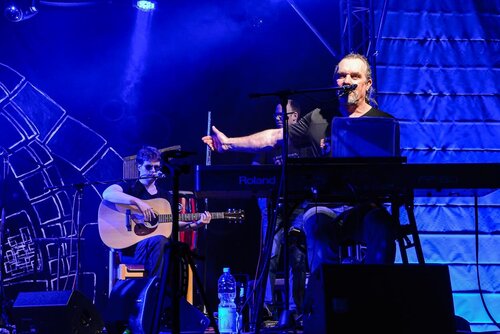 Micha Turban sitzt bei einem Konzert am Keyboard und streckt den Arm nach hinten, um die Band vorzustellen