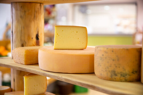 Aufgeschnittene Käse-Laibe auf in einem Holzregal