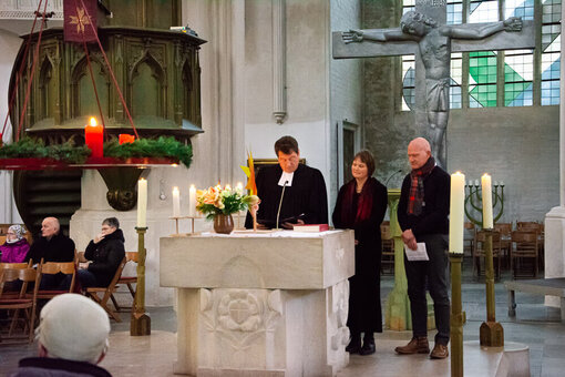 Die drei Personen stehen hinter dem Altar