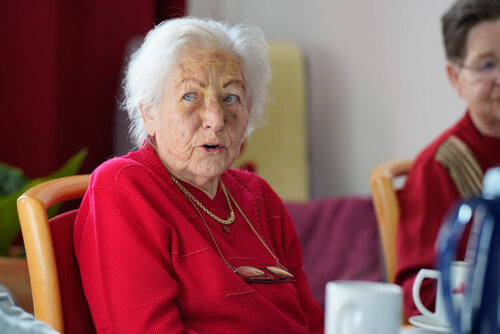 Eine ältere Frau sitzt an einem Tisch mit einem Becher