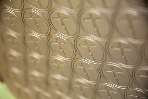 Ein Metallblech, in dem die Hostien gebacken werden, mit vielen kleinen runden Ausschneidungen in Hostienformen