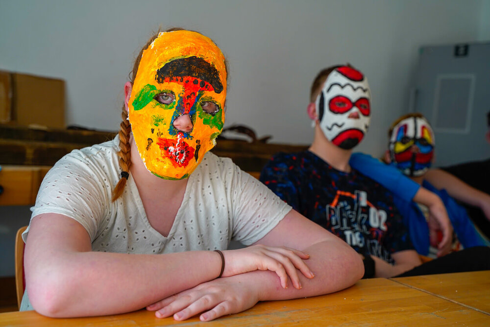 Ein Junge und ein Mädchen tragen selbst gebastelte Gesichtsmasken