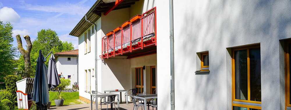 Ein zweistöckiges Gebäude mit Balkon und Sitzgruppe