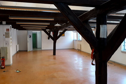 Blick in einen großen leeren Raum mit Holzgebälk zur Stützung des Daches