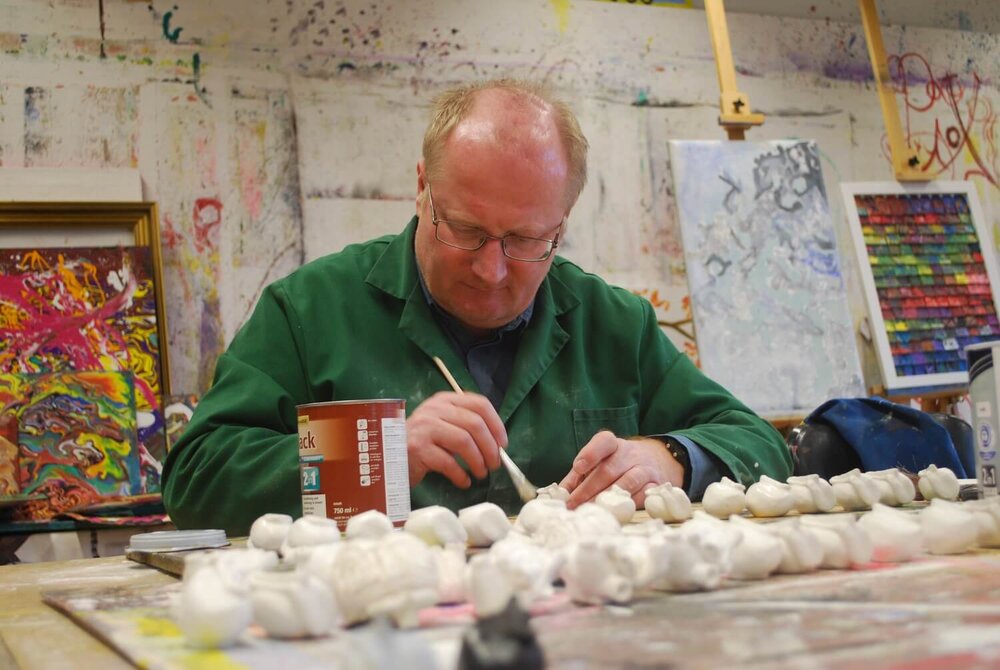 Ein Künstler im Atelier in Greifswald bemalt Figuren