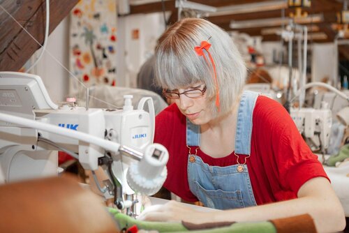 Eine Frau verarbeitet Stoffe an einer Nähmaschine Frau an Nähmaschine