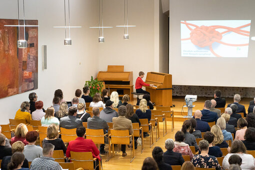 Ein Junge spielt Klavier vor einem größeren Publikum im Saal