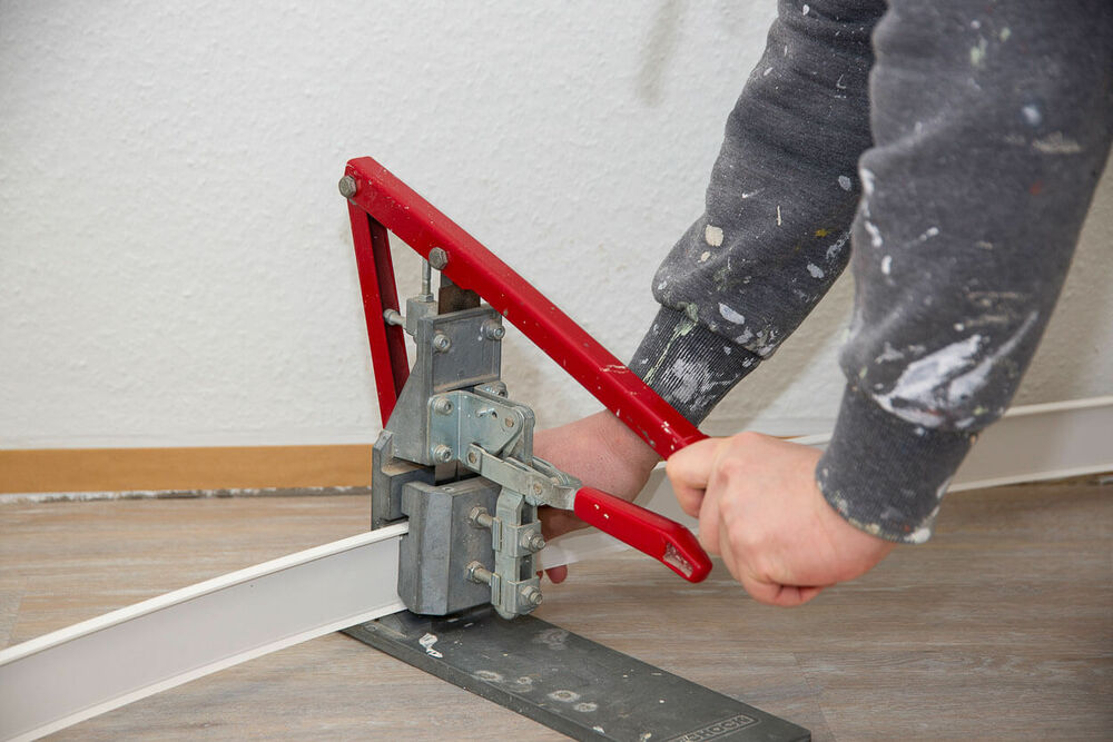 Ein Maler trennt eine Fußbodenleiste mit einem Werkzeug