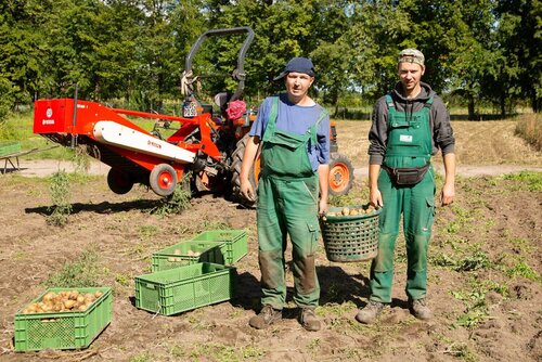 Zwei Männer in Arbeitskleidung stehen nebeneinander auf einem Acker