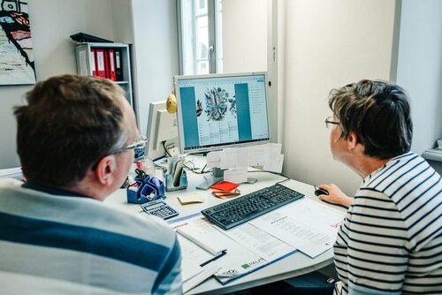 Zwei Mitarbeitende schauen auf einen Bildschirm