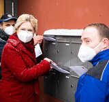 Frau Schwesig steht an einer Briefkastenanlage und wirft einen Umschlag hinein