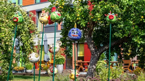 Drei handegemalte Kunstfiguren stehen auf Stützen vor einem Gebäude