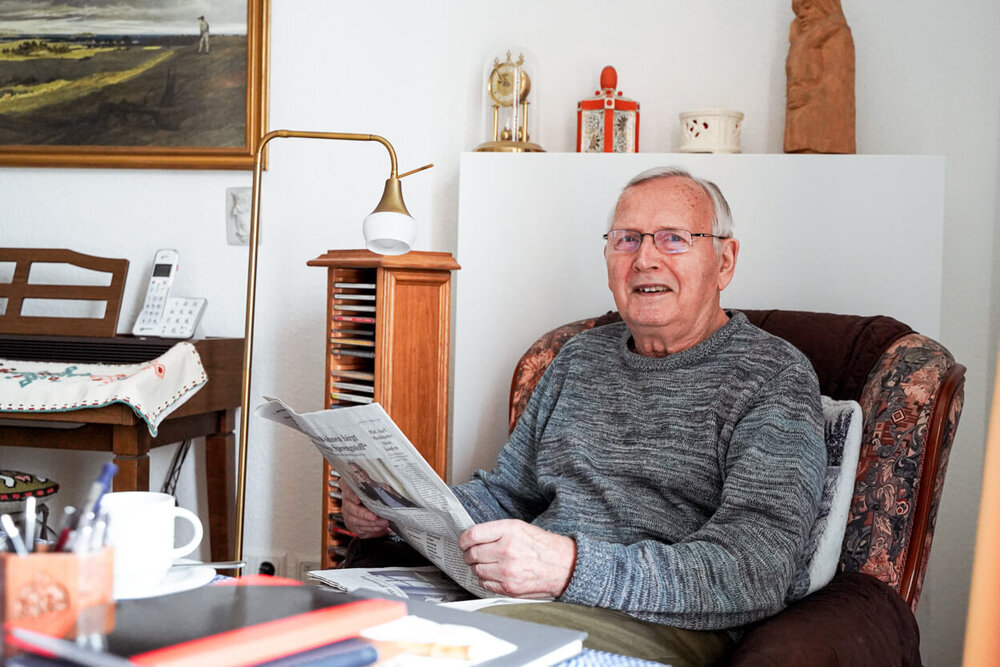 Ein älterer Herr sitzt in einem Sessel und liest Zeitung