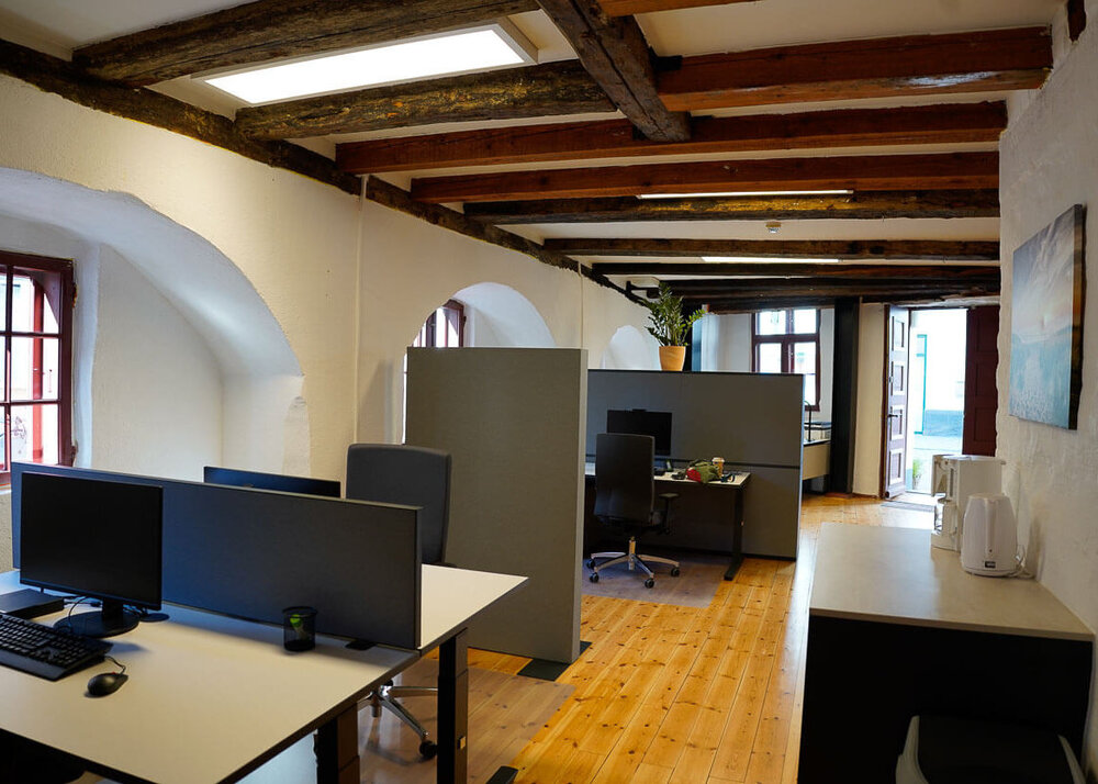 Ein Raum mit Holzfußboden, Arbeitstischen mit Monitoren und Schränken