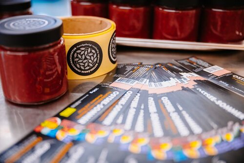 Bedruckte Etiketten liegen neben einem Glas mit Fruchtaufstrich