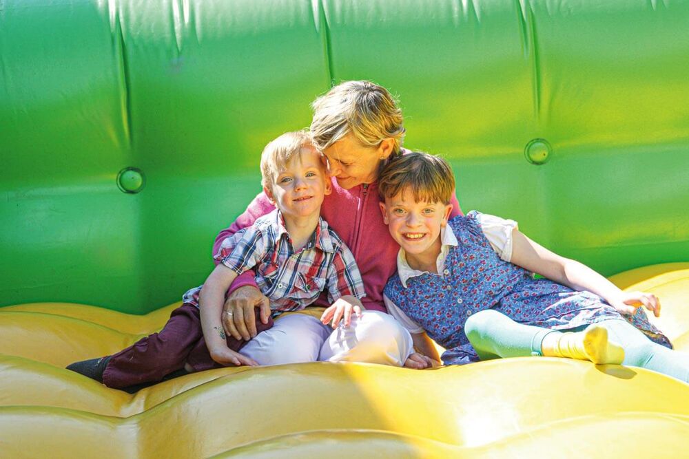 Frau mit zwei lächelnden Kindern sitzt in einer Hüpfburg bei einer Veranstaltung des Pommerschen Diakonievereins