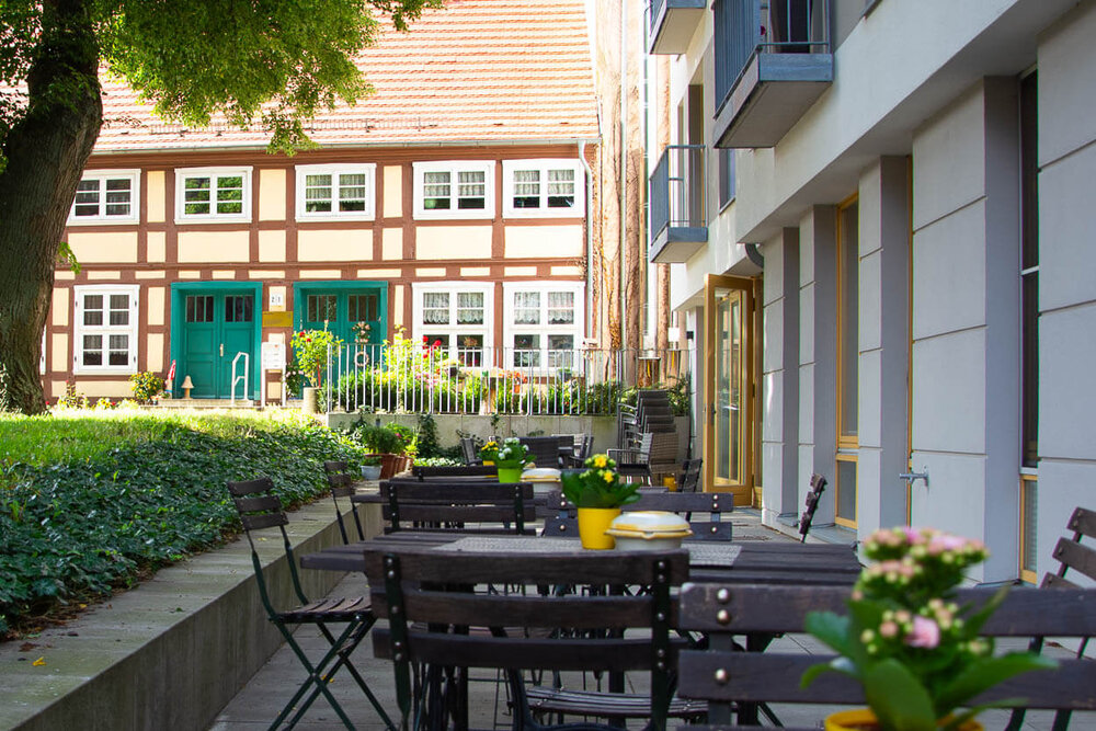 Eine Terrasse mit Tischen und Stühlen und der geöffnete Eingang der Tagesgruppe Sonnenseite in Demmin