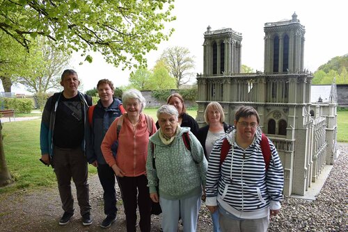 Eine Gruppe von Menschen steht vor einem kleinen Nachbau einer bekannten Kirche in Paris
