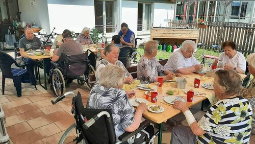 Zwei Gruppen mit Menschen sitzen an gedeckten Tischen