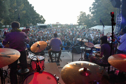 Seeside spielt auf der Bühne mit vielen Instrumenten. Davor steht eine große Menschenmenge und hört zu.