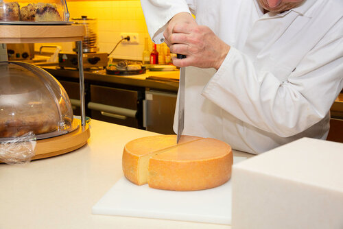 Mit einem großen Käsemesser wird ein Laib auf der Anrichte geteilt