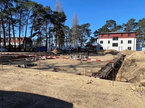 Eine große leere Baugrube mit Absperrband und einigen Baugeräten