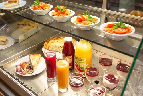 Salate, Getränke und verschiedene Speisen liegen in einer Kühlvorrichtung aus Glas